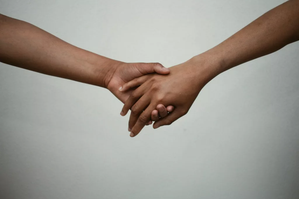 two people holding hands on white surface